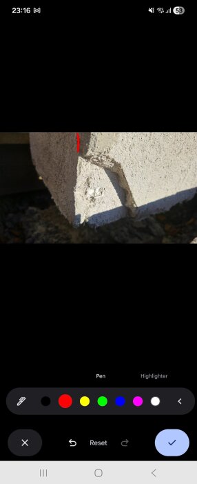 Närbild av ett husfasadhörn där det yttre putslagret är sprucket, med en kontrasterande röd linje i bilden.