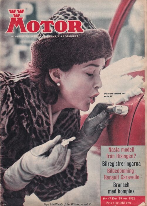 Kvinna i päls och mössa blåser på en frusen bildörrlås med en nyckel i handen, framför ett snötäckt fordon.