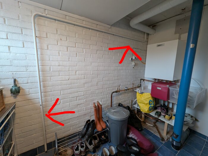 Frikopplat rör längs en vit tegelvägg i ett pannrum, med pilar som markerar rörets början och slut nära golvbrunn och pannan.*
