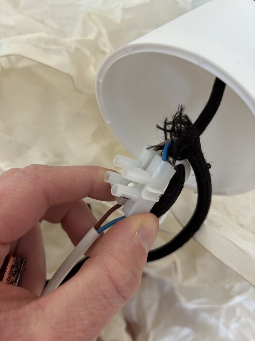 Hand håller en dubbelisolerad lampa ansluten med en WAGO-kopplingsklämma.