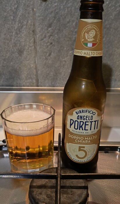 Flaska och glas med Angelo Poretti öl, placerade på en spishäll.