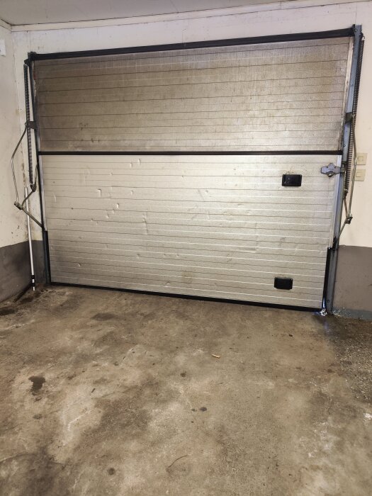 Gammal CAR-IN vikport i ett garage, med slitage och utan dörröppnare installerad.