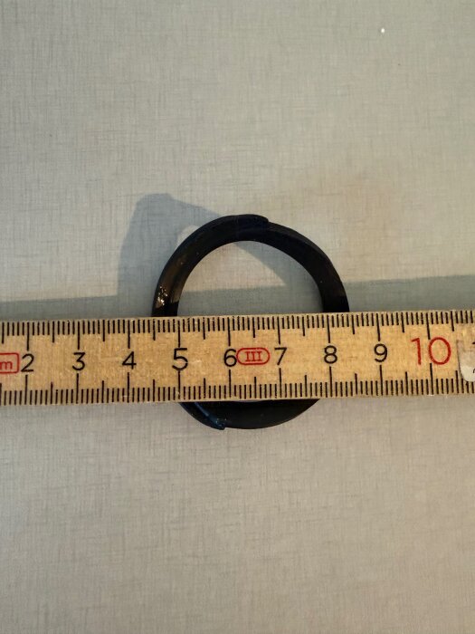 Gummiring med märklapp och måttband, längd cirka 8 cm.