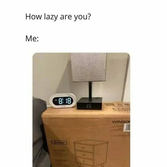 Väckarklocka och lampa placerade på en ouppackad låda med byrå, med texten "How lazy are you? Me:".