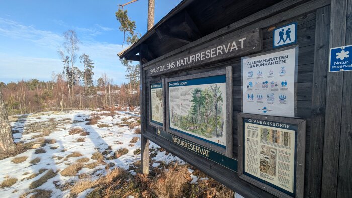 Informationsskylt i Svartdalens naturreservat om skogen och allemansrätten, med snöklädd mark och skog i bakgrunden.