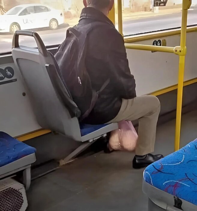 Bussresenär med ryggsäck på sätet, håller en plastpåse.