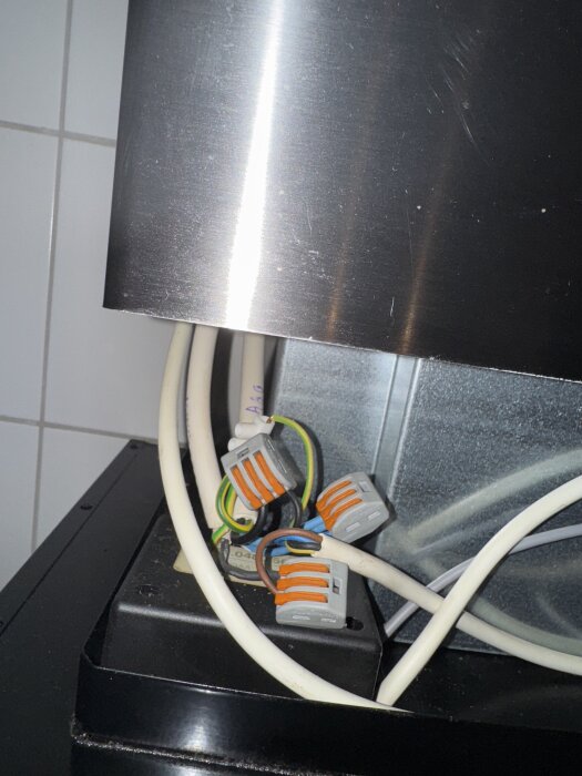 Elektriska kablar kopplade med kopplingsklämmor i ett metallhölje.