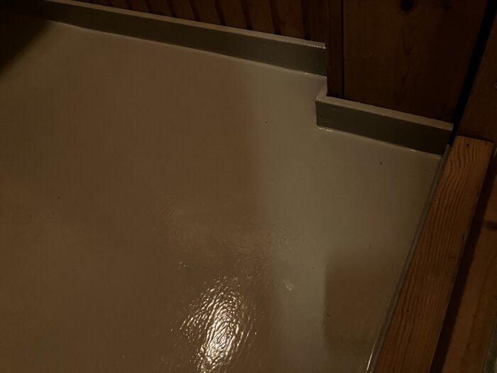 Nylackerat golv med glänsande yta och träpaneler i bakgrunden.