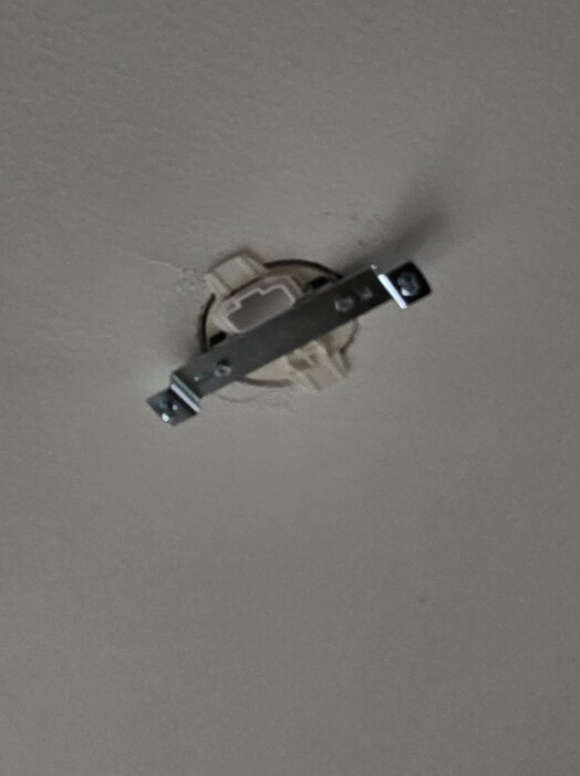 Monterad takdosa i ett betongtak med ett metallfäste fastsatt för att hänga en lampa utan borrning.