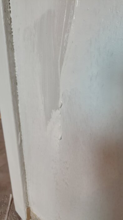 Ojämnt applicerad färg med rinningar på en vägg, visar slarvig spärrmålning.