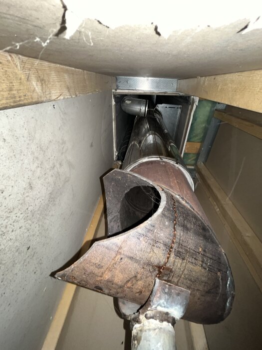 Spirorör i ett trångt schakt, delvis instängda, med synliga ventilationsdetaljer samt en träkonstruktion som omger röret.