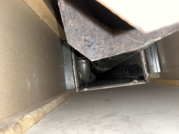 Spirorör placerade i ett trångt schakt, med ett annat fack synligt bakom. Möjlig del av en avbruten FTX-installation.