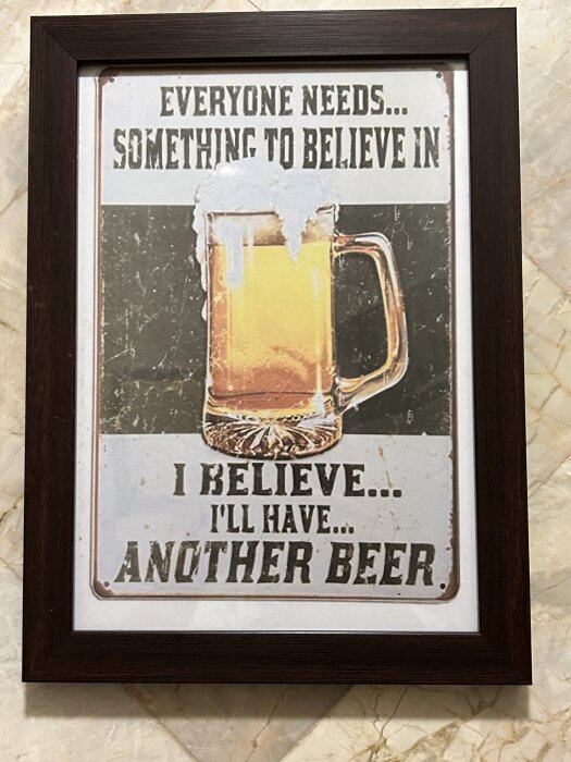 Metallskylt med texten "Everyone needs something to believe in, I believe... I'll have another beer" och en bild av ett ölglas med skum.