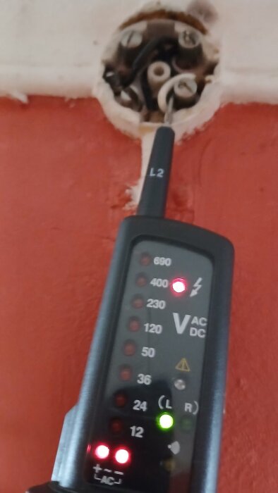 Multimeter visar 400V vid en kopplingspunkt, omgiven av flera elledningar och kopplingsplint.