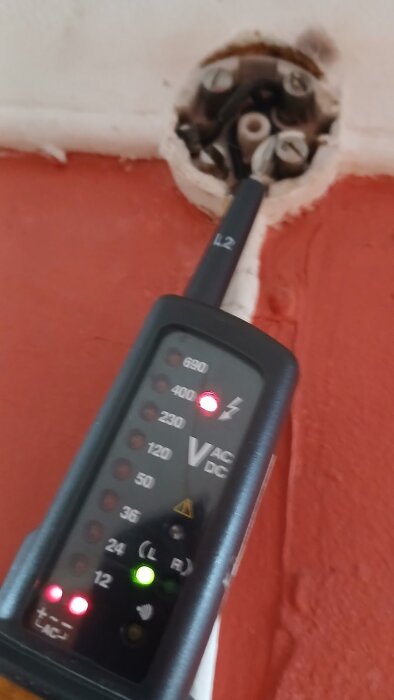 Spänningsmätare ansluten till en kopplingspunkt med röd och grön lampa tänd.