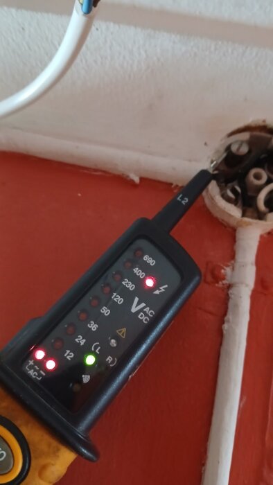 Spänningsprovare visar mätvärde vid kopplingspunkt med vit och blå kabel.