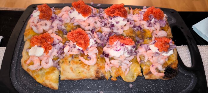 Pizza med räkor, rödlök, gräddfil och rom serverad på en ugnsplåt.