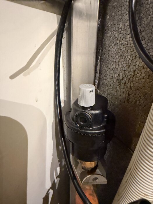 Avluftningsventil för IVT 402 FLVP värmepump, med kopplingar och rör synliga, i ett tekniskt installationsutrymme.