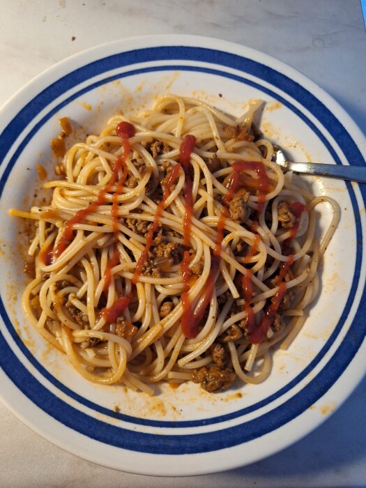Pasta med köttfärssås och ketchup på en tallrik.