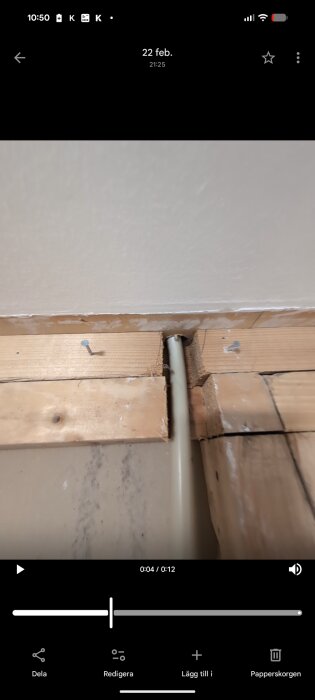 Öppnad vägg i garage med synliga reglar och en utskjutande skruv. Gipsskiva syns ovan. En rörledning går igenom väggen.