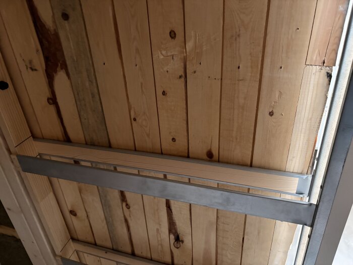 Ramen för en skjutdörr monterad i en träram av plywood, med synliga metallstöd tvärs över dörröppningen under badrumsrenovering.