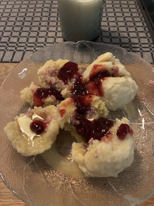 Kroppkakor med lingonsylt serverade på en tallrik med ett glas mjölk i bakgrunden.