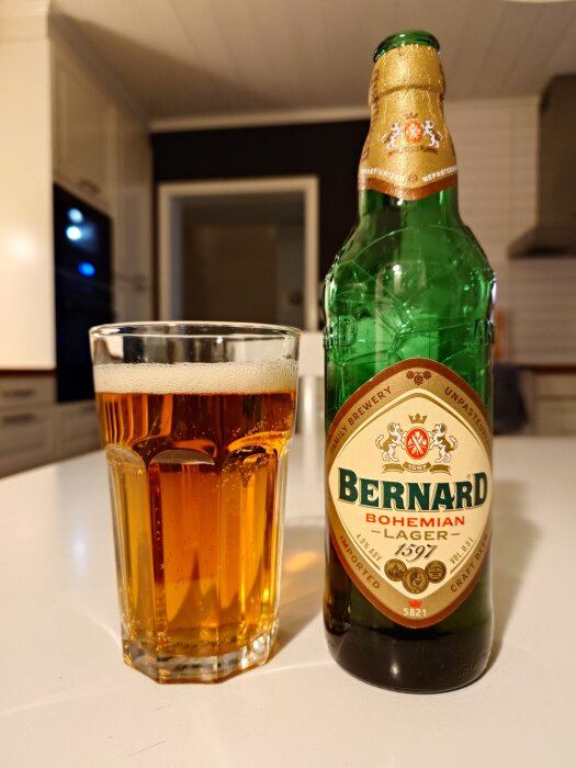Flaska och glas med Bernard Bohemian Lager på ett köksbord.