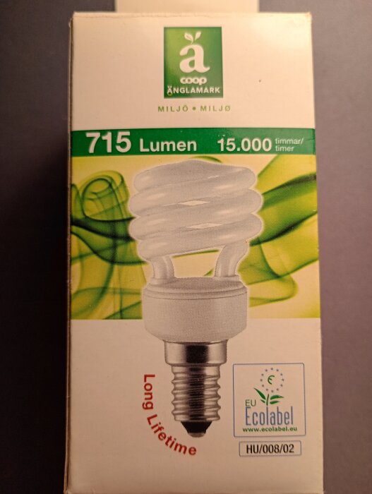 Förpackning av Änglamarks lågenergilampa, 715 lumen, 15,000 timmar. Marknadsförs som miljövänlig, innehåller EU Ecolabel och "Long Lifetime".