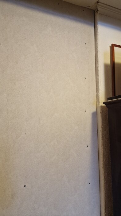 Nybyggd vägg med gips som avslutas mot en putsad murstock, visar en springa mellan gipsskivan och murstocken.