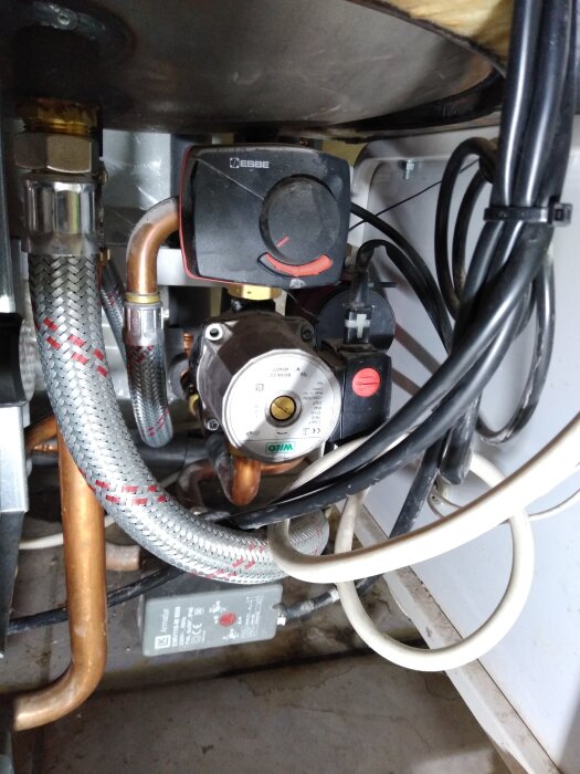 Värmepumpinstallation med cirkulationspump och justerbart vred från Esbe, omgiven av koppar- och anslutningsledningar.