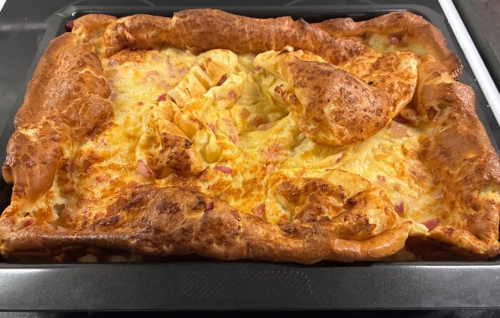 Nybakad fläskpannkaka i ugnsform, gyllenbrun och fluffig med inslag av fläskbitar.