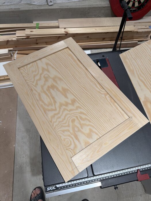 Garderobsdörrar av furu med infälld plywood, placerade på en arbetsbänk i en verkstadsmiljö.