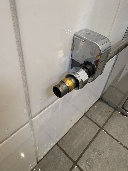 Närbild på rörinstallation med kulventil och bussning kopplade till väggmonterad vattenledning; synliga tecken på vattenläckage.
