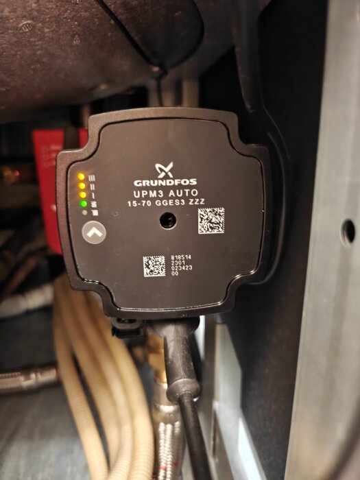 Vattenpump Grundfos UPM3 AUTO installerad i ett rörsystem, med indikeringslampor och synliga modellnummer.
