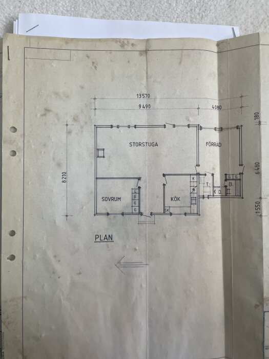 Gammal byggnadsritning från 1979 med planlösning som visar sovrum, storstuga, kök och förråd med måttangivelser och pilar.