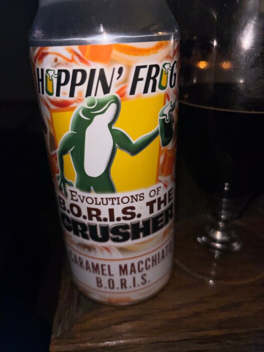 En burk med etiketten "Hoppin' Frog B.O.R.I.S. The Crusher Caramel Macchiato" bredvid ett glas med mörk dryck.