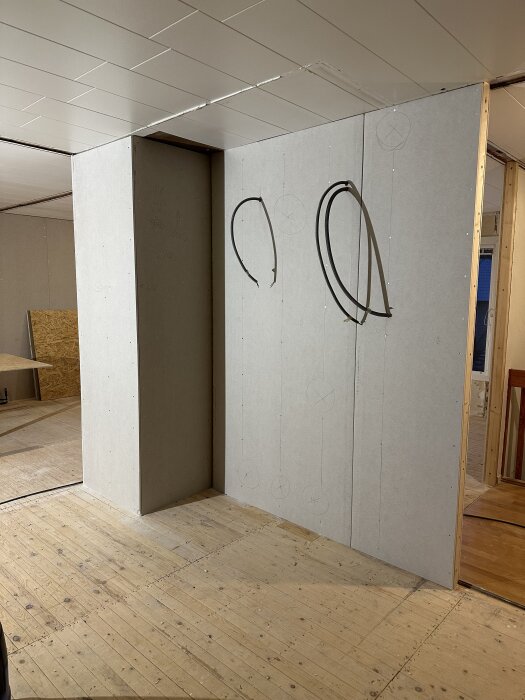 Renovering av källarutrymme med oslipat trägolv och väggar av gipsplattor med fördragna elrör.