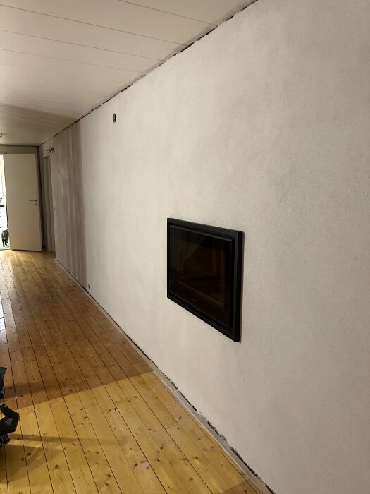 Nyrenoverad gillestuga med putsad vägg och infälld kamin, samt ljus trägolv.