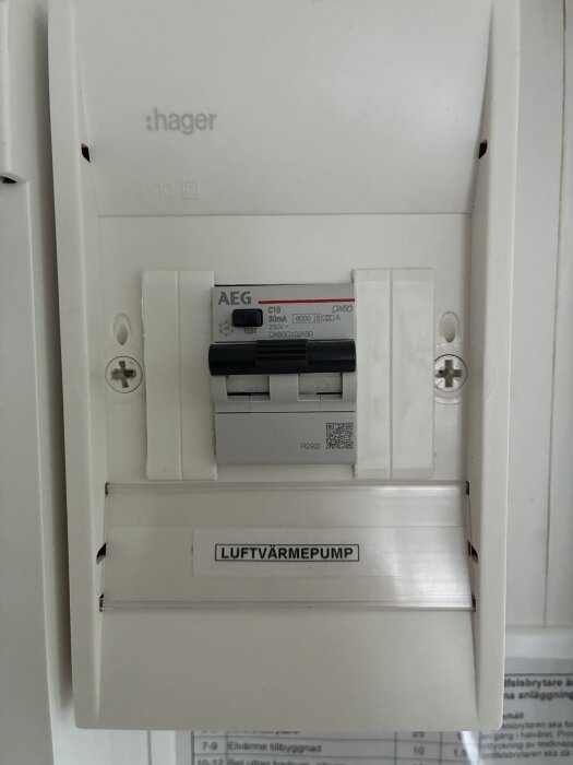Bild på elcentral med strömbrytare för luftvärmepump. Två brytare syns; en märkt AEG. Diskuteras hur strömmen ska brytas för rengöring av värmepumpen.
