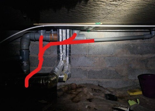 Rörledningar och ventilationsrör i källare, med några märkta i rött. Bakgrunden är en grå betongvägg.