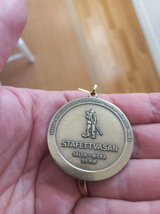 Medalj för Stafettvasan 90 km mellan Sälen och Mora, hålls i någons hand.