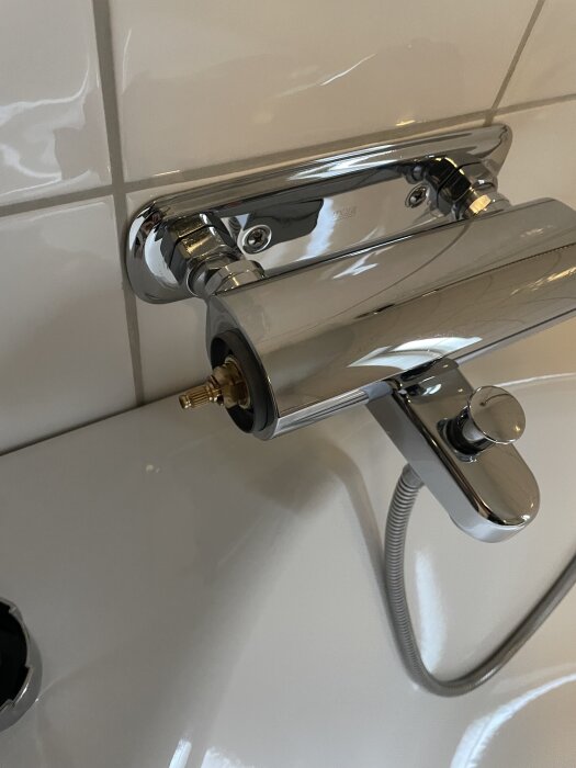 Kromfärgad duschblandare med borttagen kranöverdel på väggmonterad badrumsvägg, sett ovanifrån.