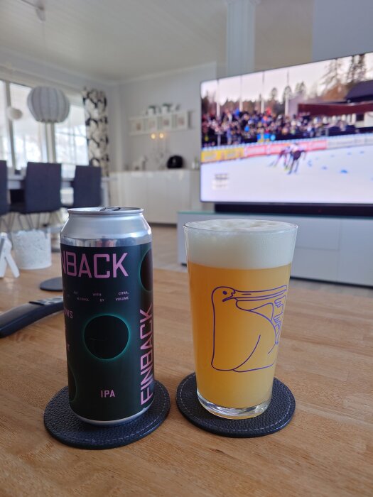 En burk och ett glas IPA från Finback på ett bord, TV visar en skidtävling i bakgrunden.