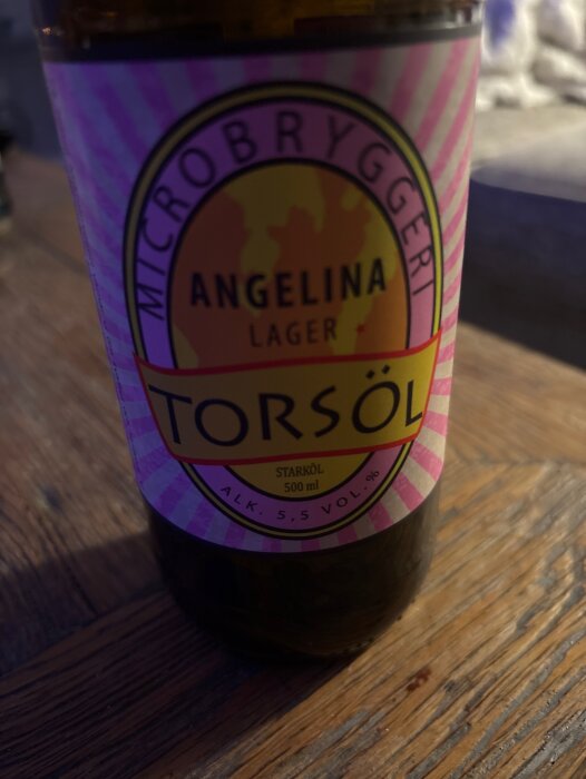 Flaska Angelina lager från Torsöl på ett träbord i dämpad belysning.