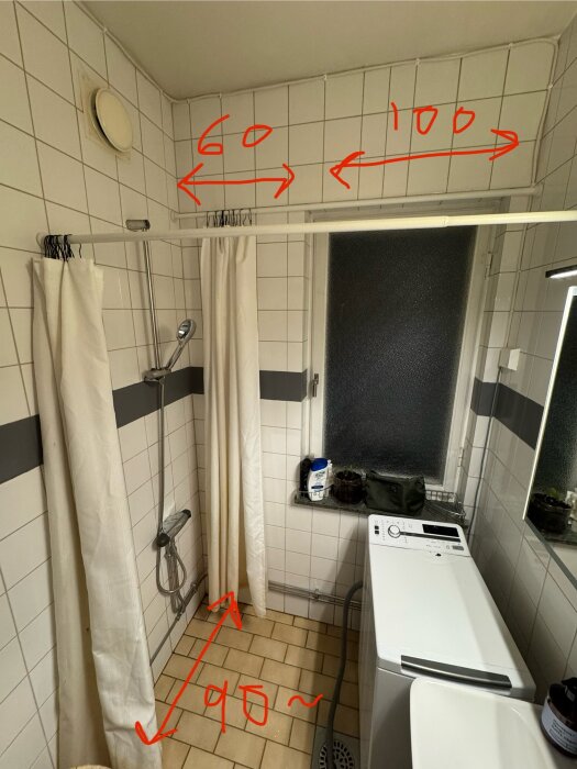 Badrum med vita kakelväggar, duschdraperi, och en vit tvättmaskin. Röda måttangivelser markerar avstånd på väggarna.