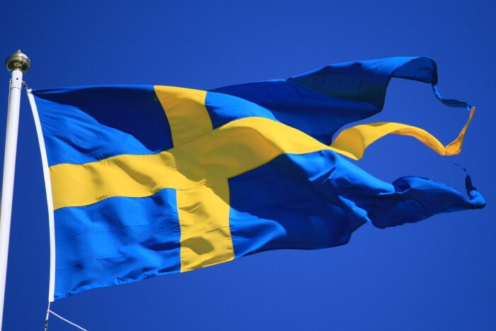 Svenska flaggan vajar mot en klarblå himmel.