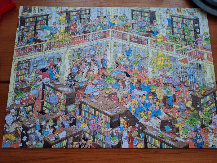 Tecknad bild av ett kaotiskt bibliotek fyllt med människor som läser, arbetar och rör sig runt bland bokhyllor och bord.