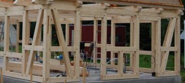 Trästomme under uppförande, visar korsvirkeshuskonstruktion med diagonalstöttor i hörn för stabilisering mot sidlaster.