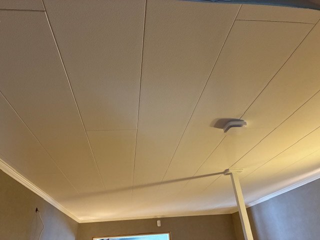 Vitt, plant innertak med paneler och infälld belysning i ett vardagsrum, där taket har måtten 30 x 240 cm.