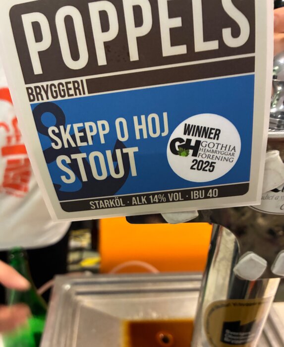 Ölkran med etikett för "Poppels Bryggeri" stout, 14% alkohol, prisad av Gothia Hembryggarförening 2025, tagen på ölmässa.